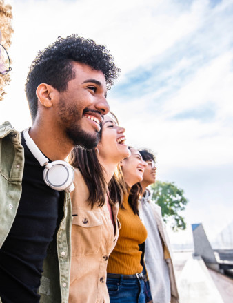 Cinq jeunes en extérieur se tiennent par les épaules.